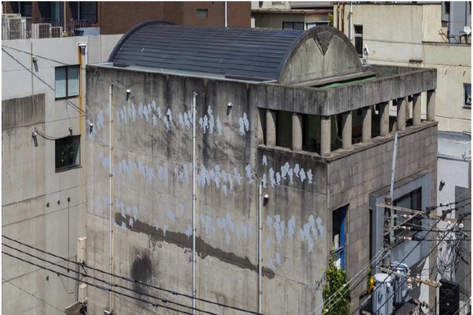 コンクリート建築の外壁を人物の列が巡るSceneの設置風景